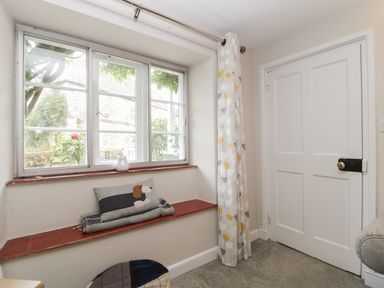 A window seat with cushions and a curtain next to a closed white door at Market House in Abbotsbury