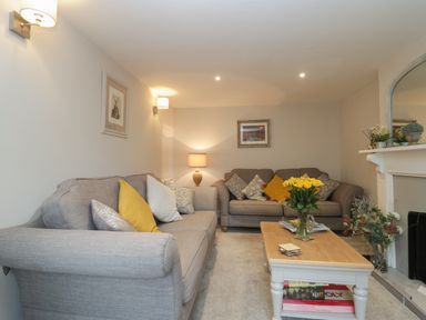 A living room with two gray sofas and a wooden coffee table with yellow flowers at Market House in Abbotsbury