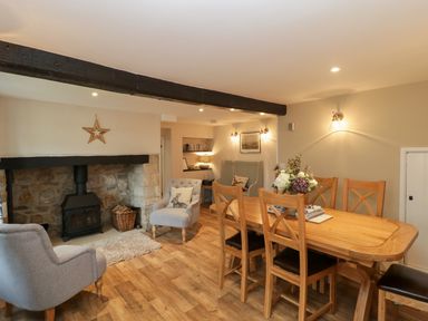 A dining room with a wooden table and chairs two armchairs a small fireplace and built in seating at Market House in Abbotsbury
