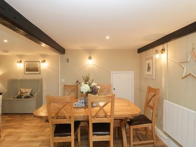 A dining room with a wooden table and six chairs and a small bench with a cushion at Market House in Abbotsbury