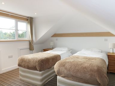 A bedroom with two single beds with brown blankets and white pillows at Crift Farm Cottage Lanlivery near Lostwithiel