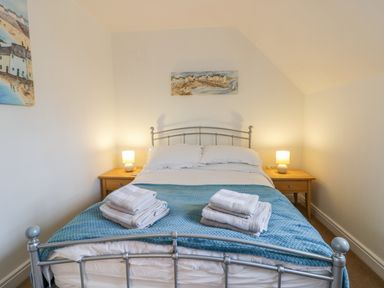 A bedroom with a metal bed frame blue blanket and two bedside tables with lamps at Bayside Cottage The Bay near Filey