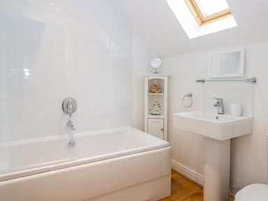 A bathroom with a bathtub a sink a small cabinet and a skylight at Bayside Cottage The Bay near Filey