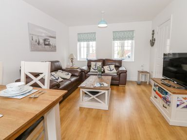 A living room with leather sofas a coffee table a television and dining table at Bayside Cottage The Bay near Filey