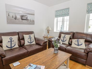 A living room with brown leather sofas and anchor themed cushions at Bayside Cottage The Bay near Filey