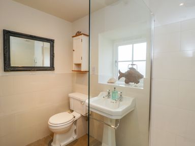 A bathroom with a toilet sink mirror window and decorative items at Wallerthwaite Barn Cottage in Markington
