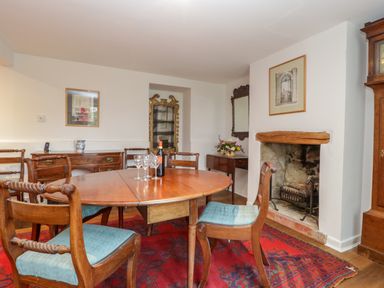 A dining room with a round wooden table and chairs near a fireplace at Church View in Salisbury