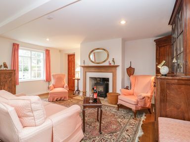 A living room with a fireplace two armchairs a sofa a wooden cabinet and a window with curtains at Church View in Salisbury