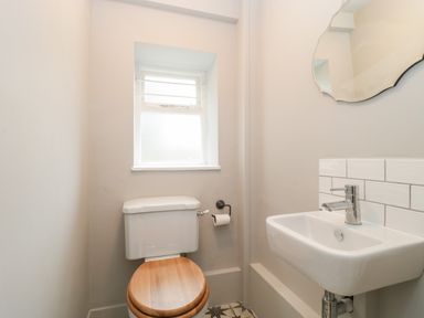 A bathroom with a toilet with wooden seat a small sink and a window at Church View in Salisbury