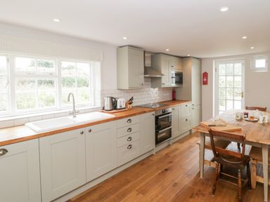 A kitchen with wooden countertop cabinets a sink stove microwave wooden table and chairs at Church View in Salisbury