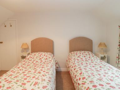A bedroom with two single beds with floral bedspreads and bedside tables with lamps at Church View in Salisbury