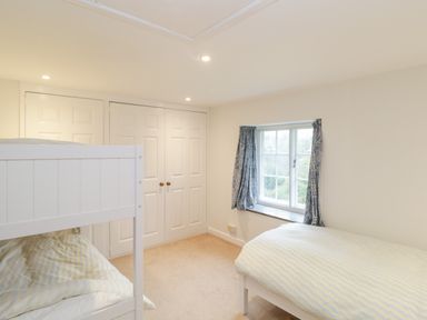 A bedroom with a bunk bed and a single bed near a window with curtains at Church View in Salisbury