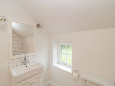A bathroom with a sink and mirror and a window next to a toilet at Church View in Salisbury