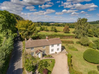 A two story house with a tiled roof and garden next to a country road surrounded by fields at Church View in Salisbury