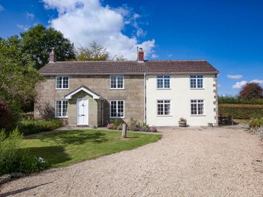 A detached house with stone and white exterior walls a lawn and gravel driveway at Church View in Salisbury