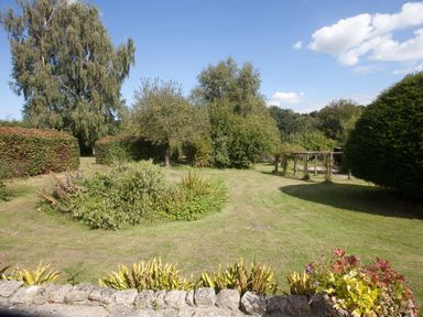 A garden with lawn bushes and trees under a blue sky at Church View in Salisbury