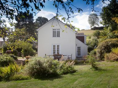 A white two-story house with a garden and outdoor furniture surrounded by greenery at Church View in Salisbury