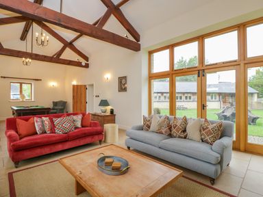 A living room with red and grey sofas and wooden beams at Lower Farm Barn Aston Near Bampton