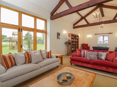 A living room with sofas cushions table bookshelf and a pool table at Lower Farm Barn in Aston Near Bampton