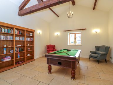 A game room with a pool table two armchairs and a bookshelf at Lower Farm Barn Aston Near Bampton