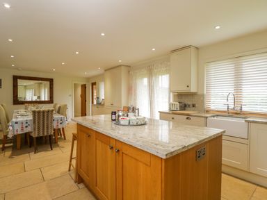 A kitchen with an island and dining table with chairs at Lower Farm Barn in Aston Near Bampton