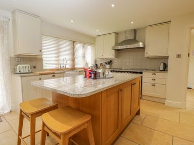 A kitchen with a large island and two wooden stools at Lower Farm Barn Aston Near Bampton