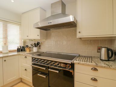 A kitchen with a black oven stove and stainless steel range hood cream cabinets and kitchen utensils at Lower Farm Barn Aston Near Bampton