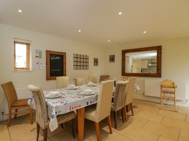 A dining room with a rectangular table set for six and a large wooden framed mirror at Lower Farm Barn Aston Near Bampton