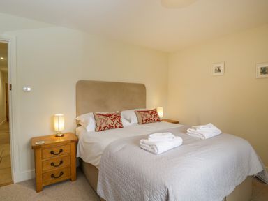 A bedroom with a double bed with two folded towels bedside tables with lamps and framed pictures on the wall at Lower Farm Barn Aston Near Bampton