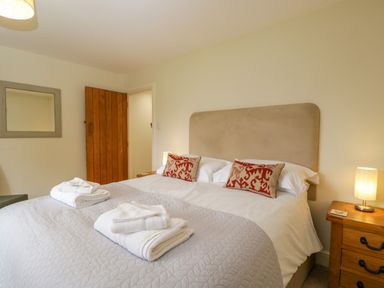 A bedroom with a double bed folded towels on the bed and a wooden door at Lower Farm Barn Aston Near Bampton