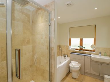 A bathroom with a glass shower enclosure bathtub toilet sink and a window with blinds at Lower Farm Barn Aston Near Bampton