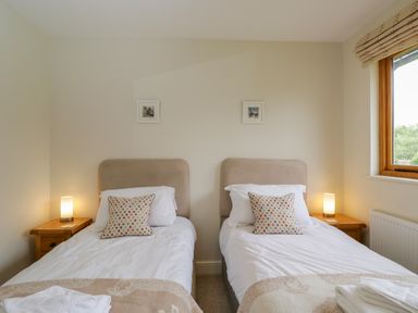 A bedroom with two single beds side by side two bedside tables with lamps and a window at Lower Farm Barn Aston Near Bampton