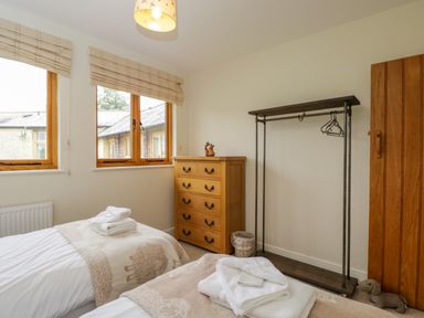 A bedroom with two single beds wooden chest of drawers and a clothing rack at Lower Farm Barn in Aston Near Bampton
