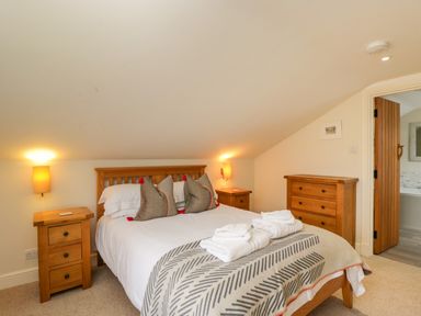 A bedroom with a wooden bed framed by bedside tables and a chest of drawers at Lower Farm Barn Aston Near Bampton