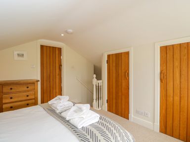 A bedroom with a bed and folded towels three wooden doors and a wooden dresser at Lower Farm Barn Aston Near Bampton