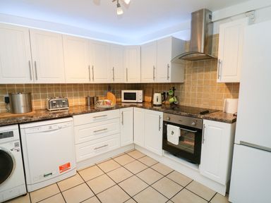 A kitchen with white cabinets and appliances including a washing machine dishwasher microwave and refrigerator at Giddy Goose in Windermere