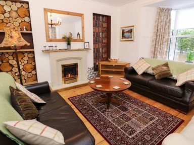 A living room with two leather sofas a round wooden coffee table a fireplace and a rug at Giddy Goose in Windermere