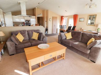 A living room with two brown sofas with yellow cushions and a wooden coffee table at Percy Wood Country Park in Swarland