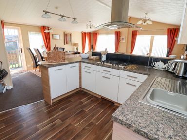 A kitchen with a sink stove and dining area visible through the open space at Percy Wood Country Park in Swarland