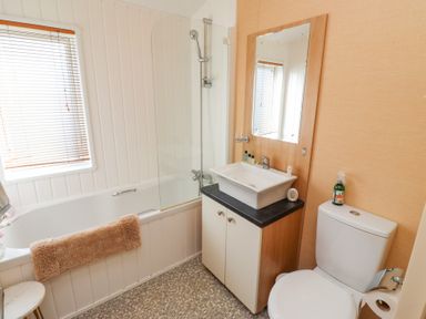 A bathroom with a bathtub a sink with a mirror and a toilet at Percy Wood Country Park in Swarland