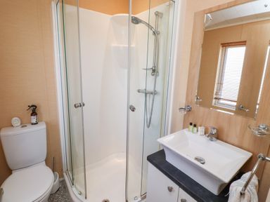A bathroom with a shower enclosure a toilet and a sink with a mirror at Percy Wood Country Park in Swarland