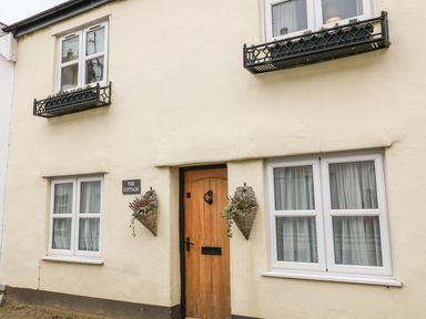 A cottage exterior with a wooden door two windows with flower boxes and wall planters at Beach Retreat in Instow