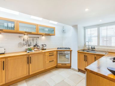 A kitchen with wooden cabinets a built in oven a sink and kitchen utensils at Beach Retreat in Instow