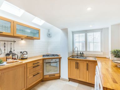 A kitchen with wooden cabinets and countertops a gas stove oven a double sink and kitchen utensils at Beach Retreat in Instow