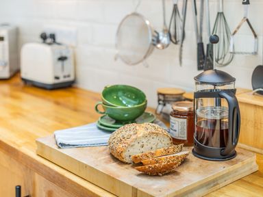 A kitchen countertop with sliced bread a French press coffee maker green bowls and a jar of marmalade at Beach Retreat in Instow