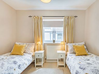 A bedroom with two single beds and a window between them at Beach Retreat in Instow