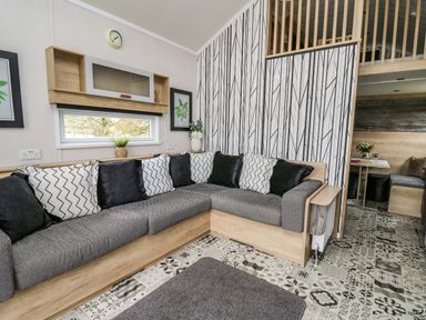 A living room with a corner sofa and patterned cushions at Meadow Retreat in Nantmel near Rhayader