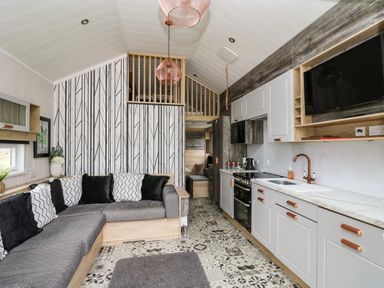 A kitchen and living area with a corner sofa and patterned floor at Meadow Retreat in Nantmel near Rhayader