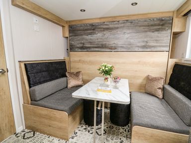 A dining area with a marble table between two bench seats and a flower vase at Meadow Retreat in Nantmel near Rhayader