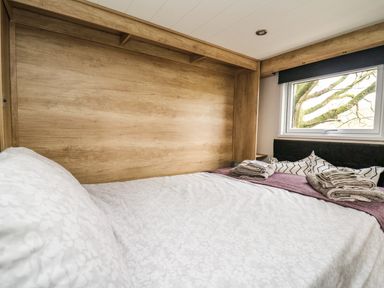 A bedroom with a bed covered with white sheets and folded towels near a window at Meadow Retreat in Nantmel near Rhayader